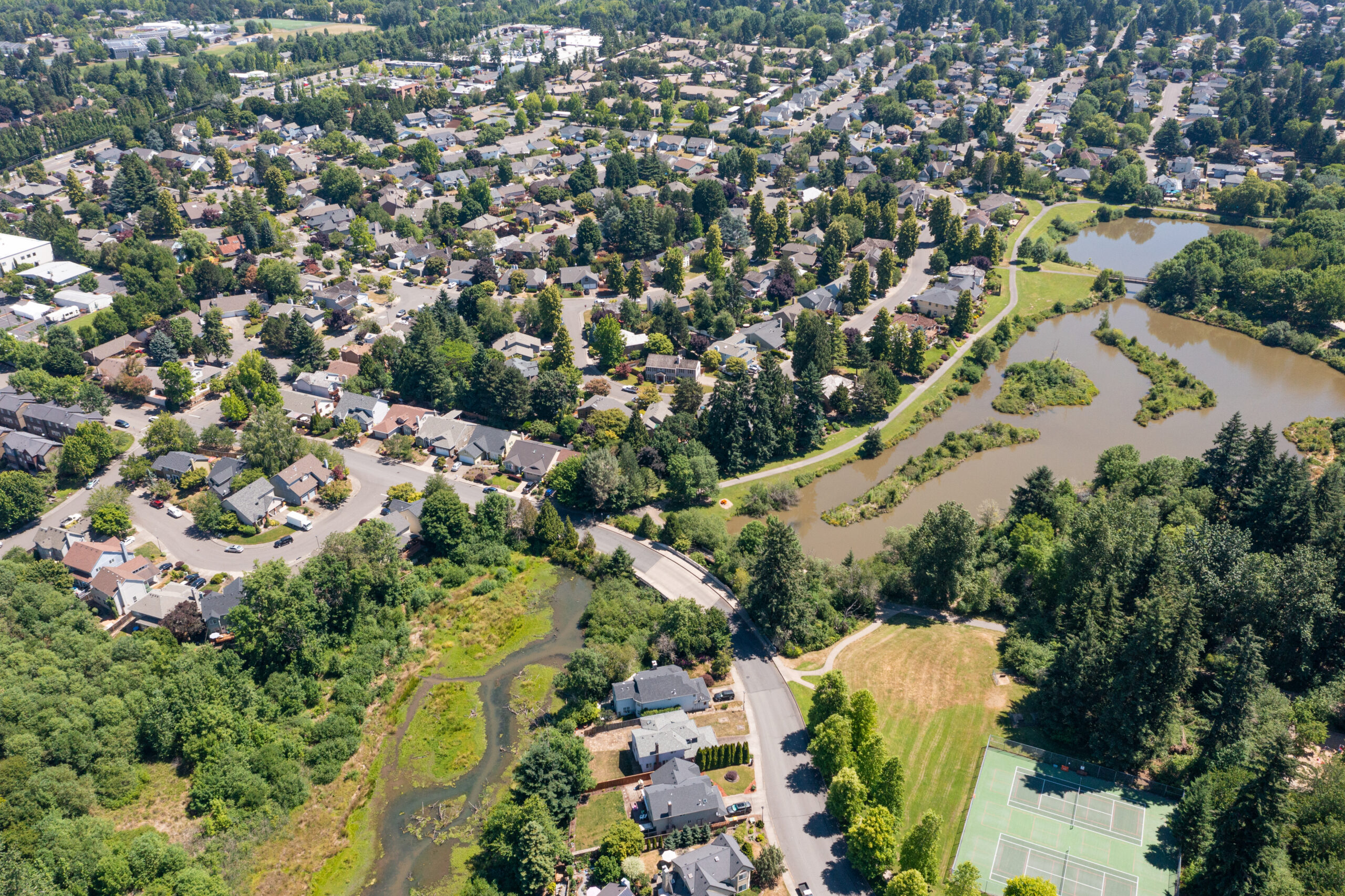 Aerial drone view of Summerlake City Park in Tigard, Oregon, showcasing Stark Reservoir, sports fields, walking trails, lush greenery, picnic areas, and surrounding residential neighborhoods